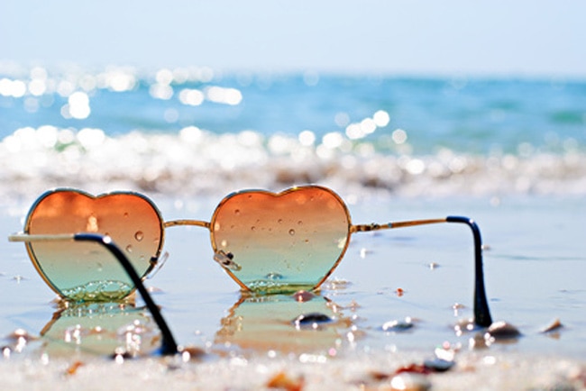 Lunettes de soleil teintées en forme de coeur dans le sable en bord de mer