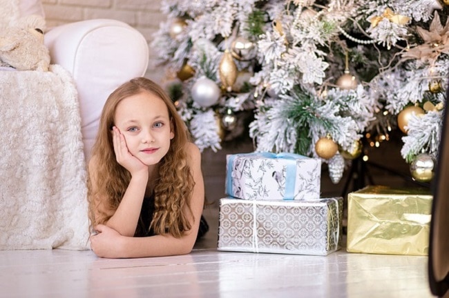 petite fille avec ses cadeaux sous le sapin de Noël