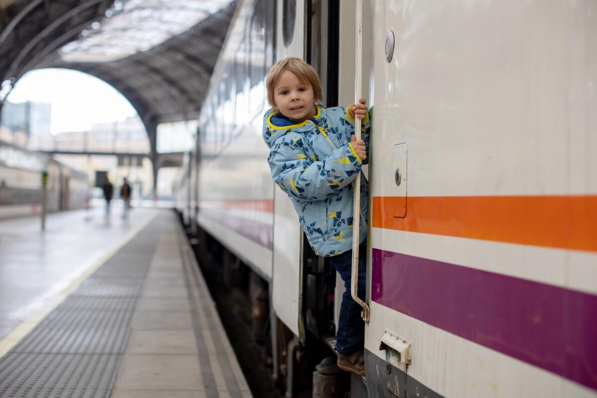Petit garçon sur le marchepied d'un train en gare, illustration du débat sur les wagons sans enfants