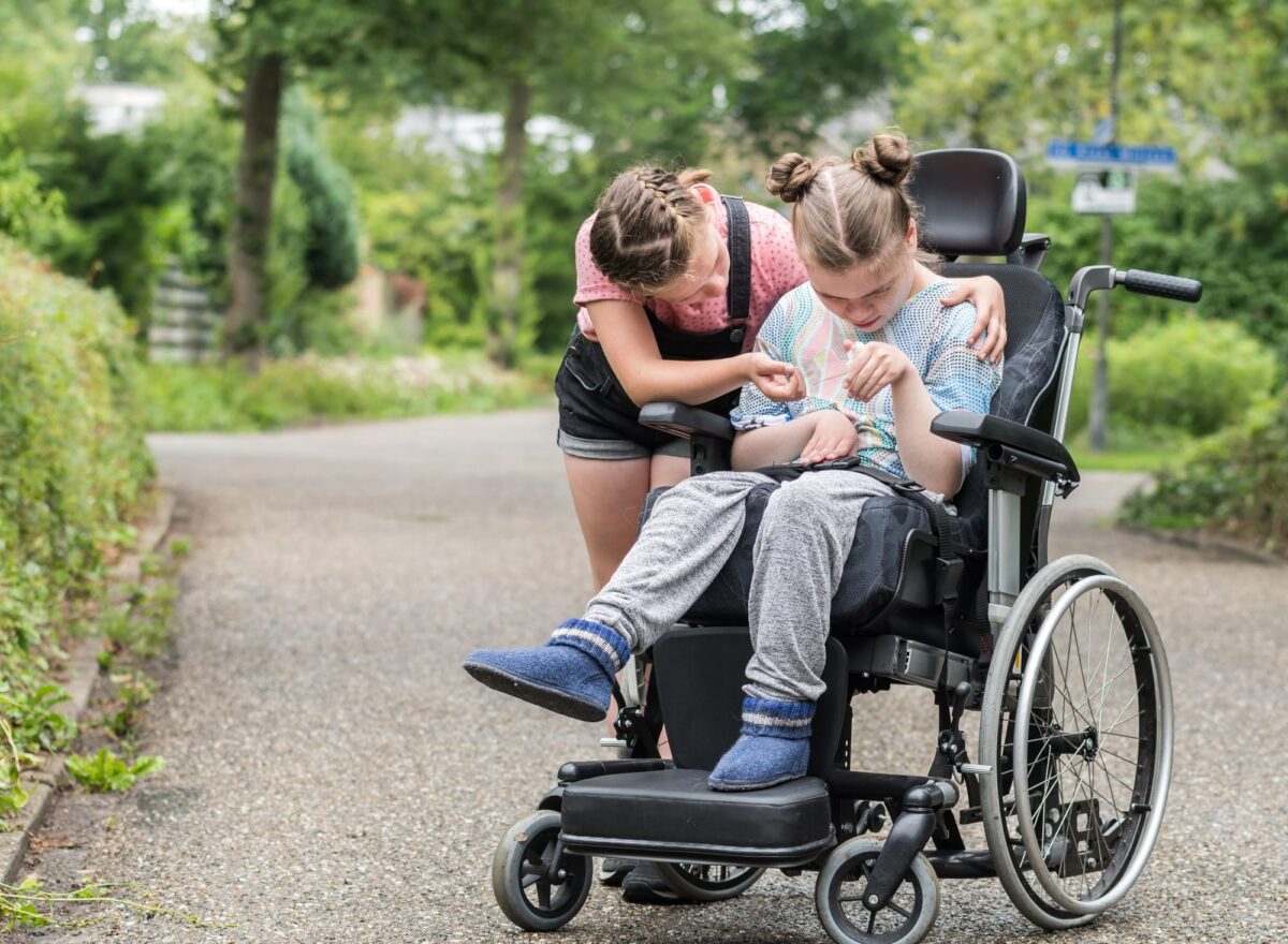 jeune fille aide sa soeur handicapée en fauteuil